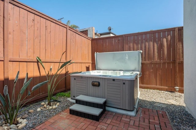 view of patio / terrace featuring a hot tub and fence