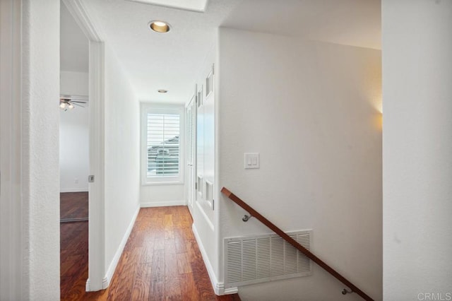 corridor featuring baseboards, wood finished floors, and visible vents