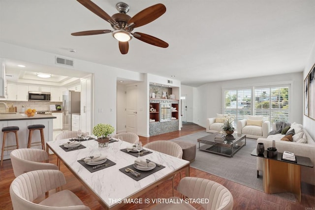 living room featuring ceiling fan, visible vents, and wood finished floors
