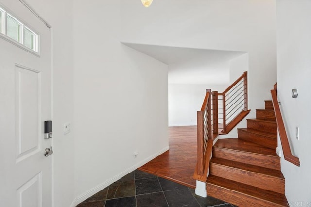 foyer entrance with stairway and baseboards