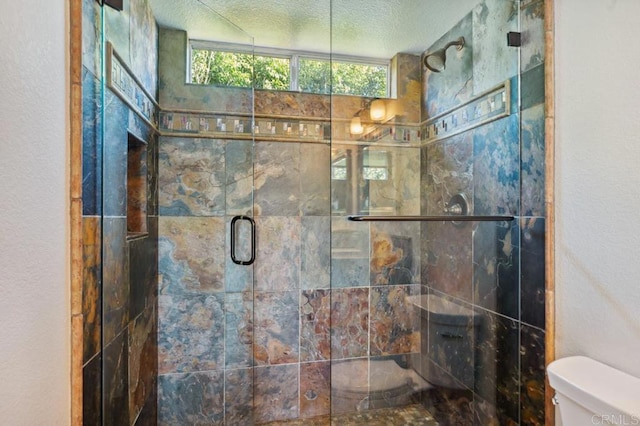 bathroom with toilet, a textured ceiling, and a stall shower
