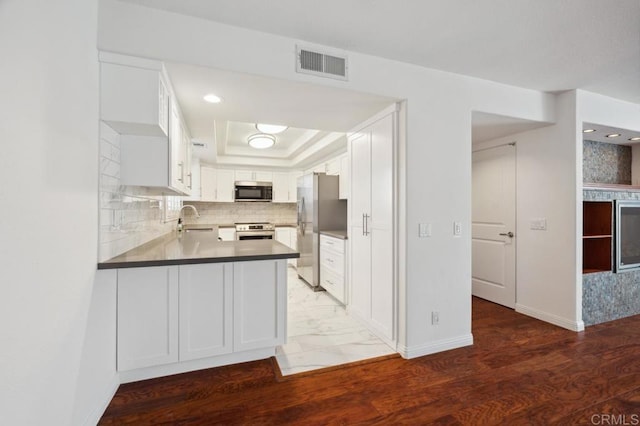 kitchen with visible vents, a peninsula, baseboards, a sink, and stainless steel appliances