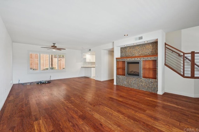 unfurnished living room featuring visible vents, wood finished floors, baseboards, a tile fireplace, and a ceiling fan