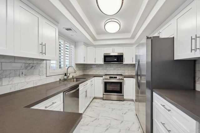 kitchen with dark countertops, appliances with stainless steel finishes, a sink, and marble finish floor