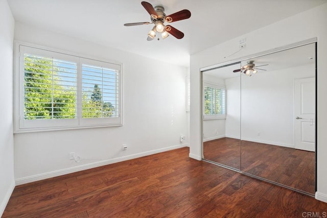unfurnished bedroom featuring baseboards, ceiling fan, wood finished floors, and a closet