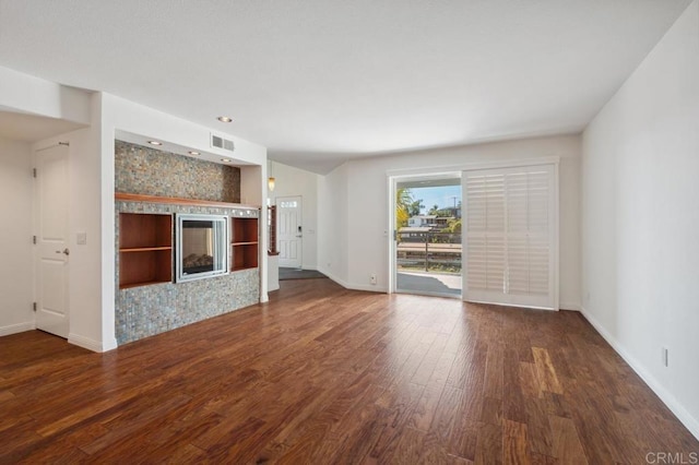 unfurnished living room with baseboards, a tile fireplace, wood finished floors, and visible vents
