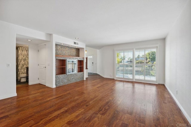 unfurnished living room featuring baseboards, wood finished floors, and visible vents
