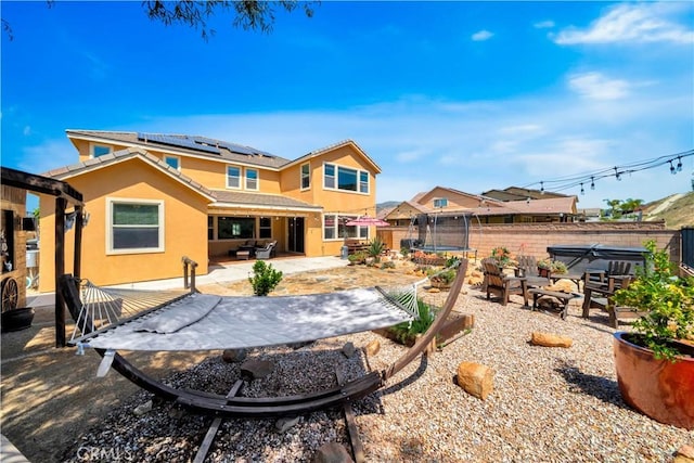 26165 Santiago Canyon Rd, Corona, CA 92883 - rear view of property featuring a trampoline, a patio, stucco siding, a fenced backyard, and roof mounted solar panels