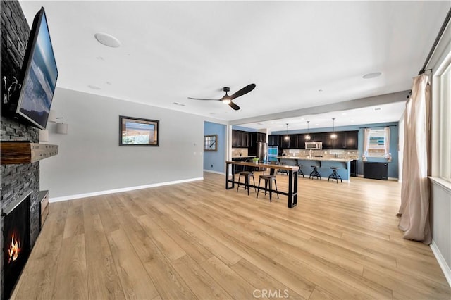 26165 Santiago Canyon Rd, Corona, CA 92883 - living area featuring a fireplace, ceiling fan, baseboards, and light wood finished floors