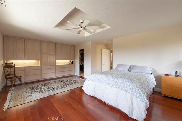 bedroom with baseboards, a closet, a ceiling fan, a tray ceiling, and hardwood / wood-style floors