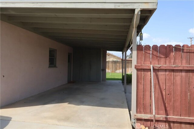 view of parking / parking lot with fence and an attached carport