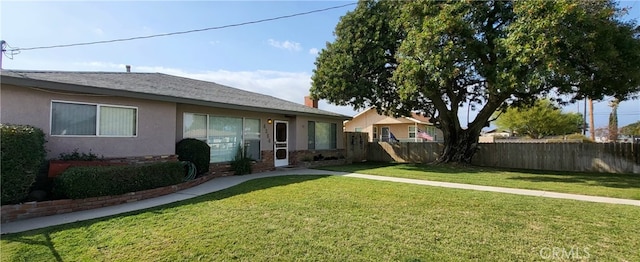 view of front of house featuring stucco siding, fence, a chimney, and a front yard