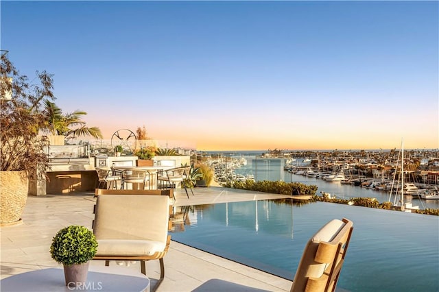1231 Dolphin, Corona Del Mar, CA 92625 - pool at dusk with a water view, exterior kitchen, and a patio area