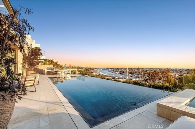 1231 Dolphin, Corona Del Mar, CA 92625 - pool at dusk featuring a patio and a water view