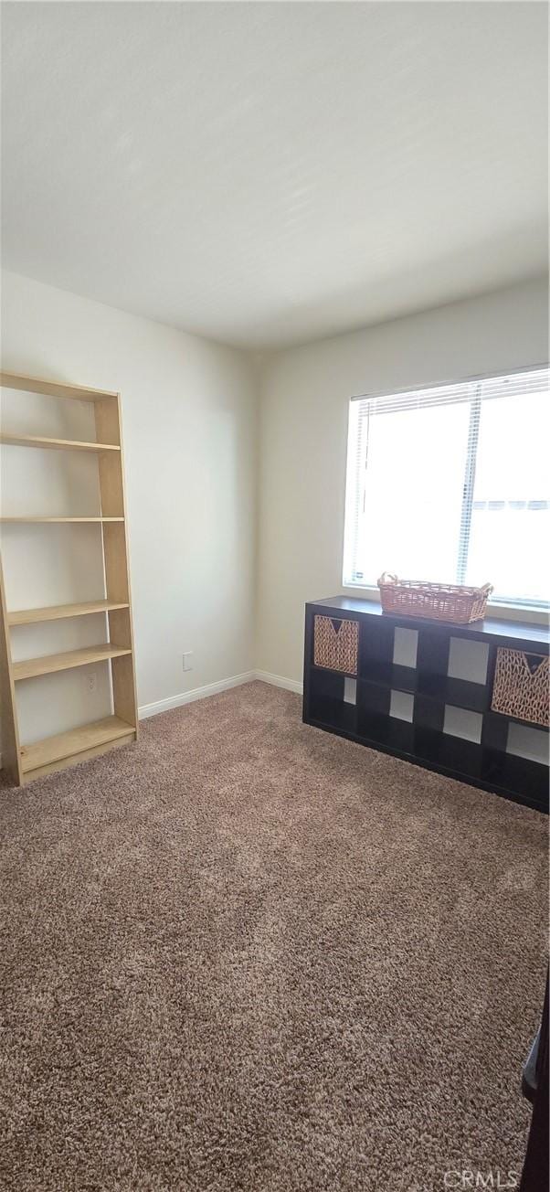 carpeted empty room with baseboards