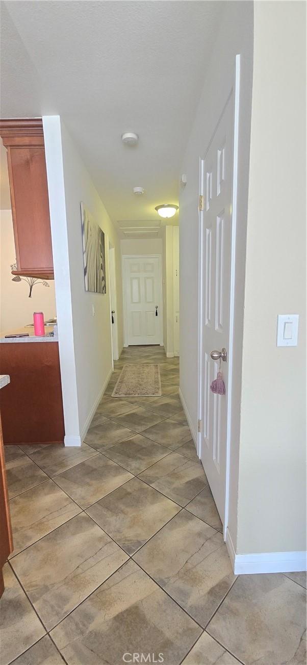 corridor with baseboards and light tile patterned floors
