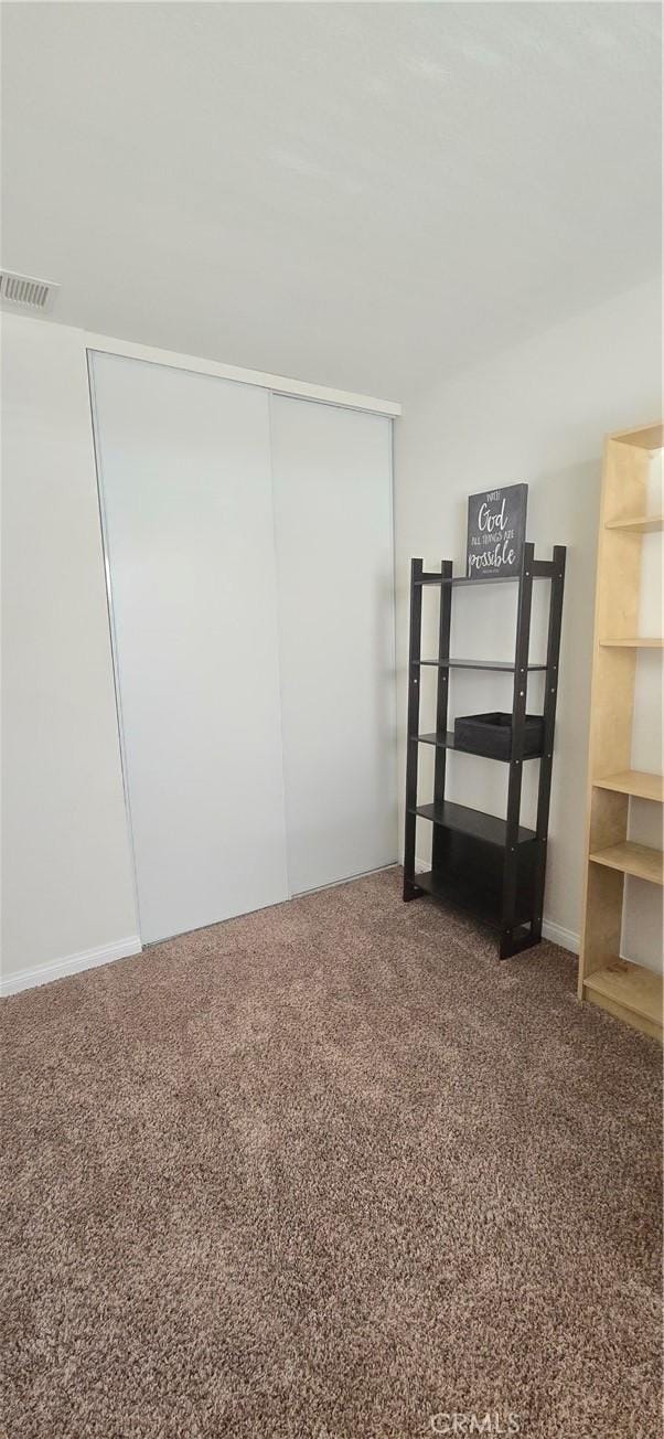 unfurnished bedroom featuring carpet floors, visible vents, and a closet
