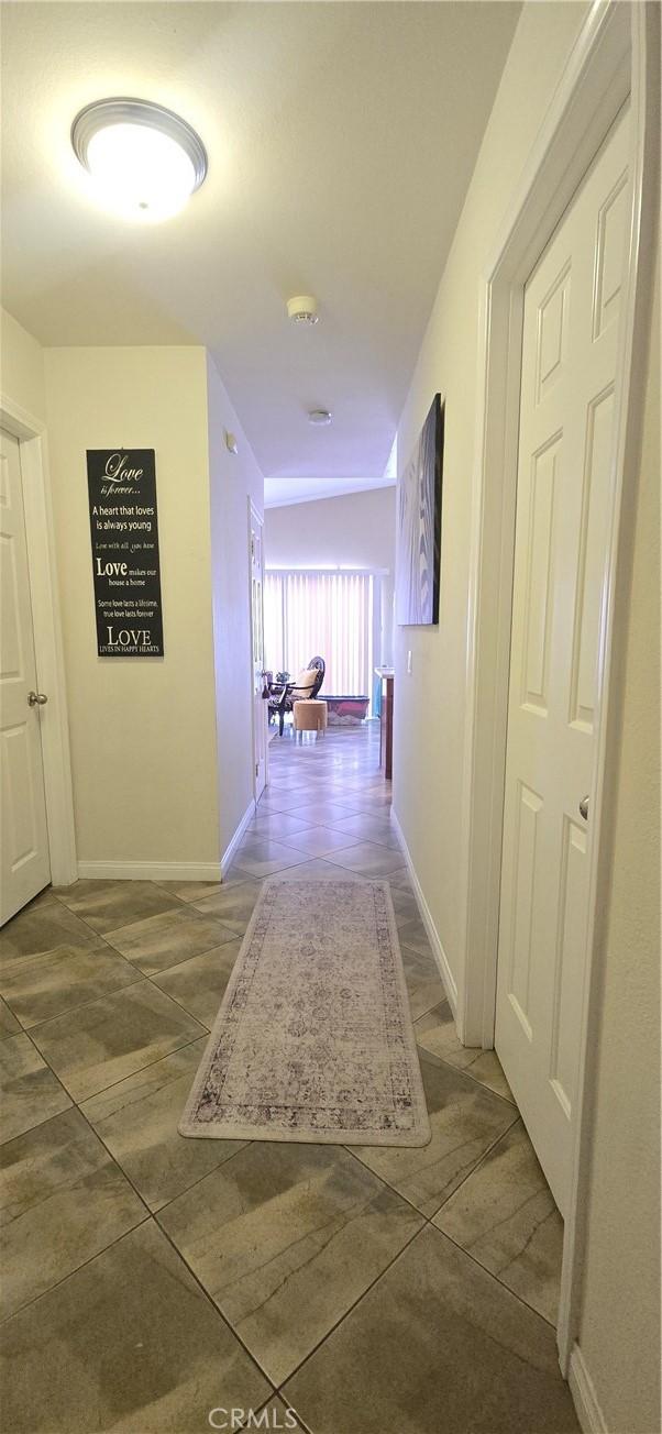 hallway with baseboards and tile patterned flooring