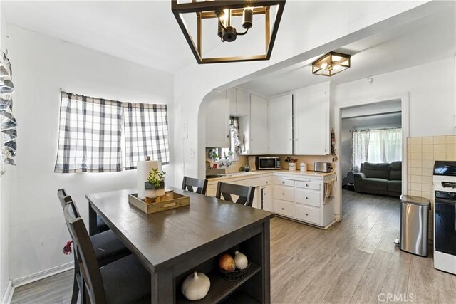 2965 Poplar Dr, Lynwood, CA 90262 - dining area featuring a chandelier, arched walkways, and light wood-type flooring