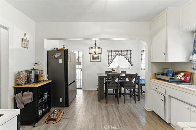 2965 Poplar Dr, Lynwood, CA 90262 - kitchen with freestanding refrigerator, light countertops, white cabinets, light wood-type flooring, and a chandelier