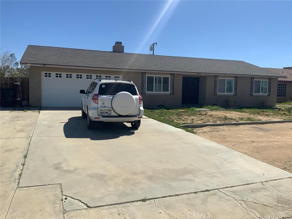 ranch-style house featuring driveway, a chimney, an attached garage, and stucco siding