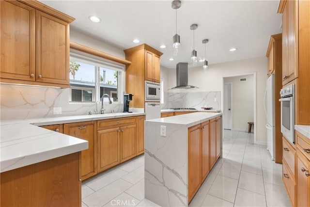 kitchen with tasteful backsplash, white appliances, a sink, a center island, and wall chimney exhaust hood