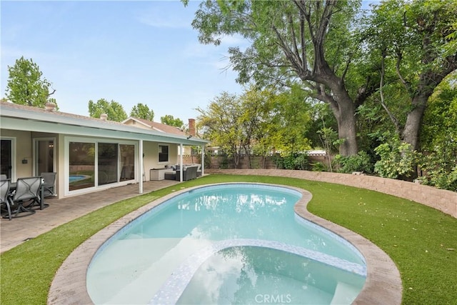 view of swimming pool with a patio, a fenced backyard, a pool with connected hot tub, and a lawn