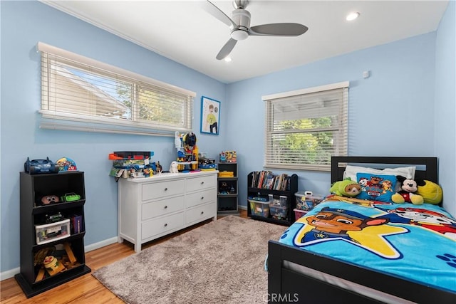bedroom featuring light wood finished floors, a ceiling fan, multiple windows, and baseboards