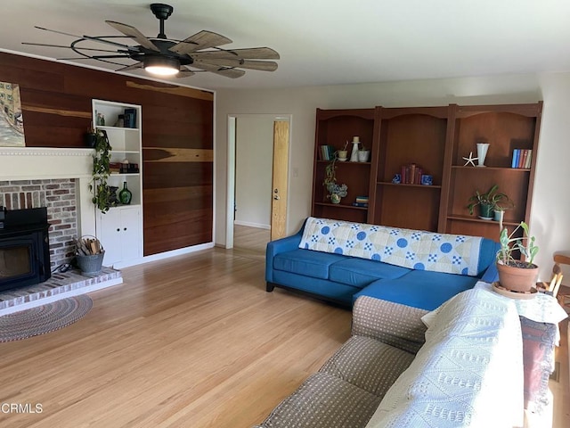 living area with wooden walls, wood finished floors, baseboards, and ceiling fan