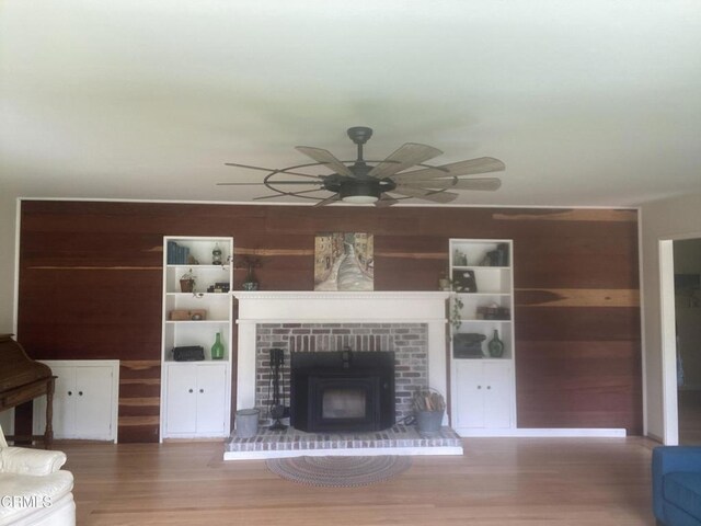 unfurnished living room with wood finished floors, a wood stove, wood walls, and a ceiling fan