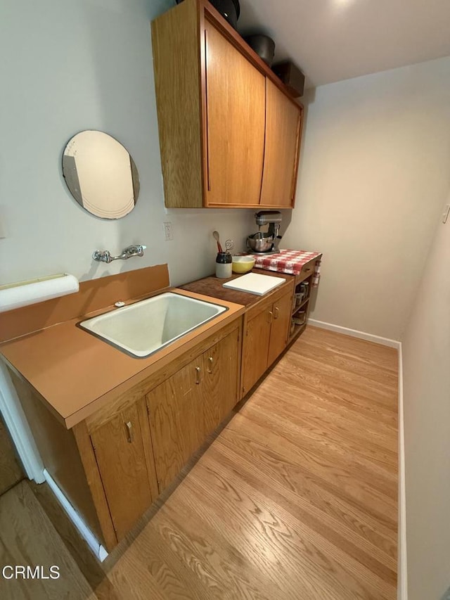 kitchen featuring brown cabinetry, a sink, and light wood-style floors