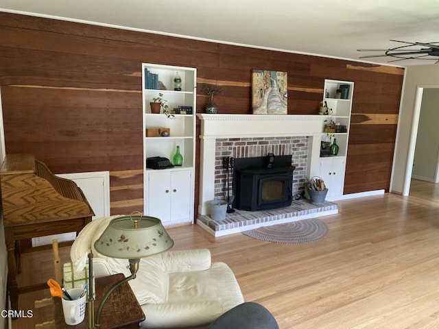 living room featuring ceiling fan, wood finished floors, wood walls, and a wood stove