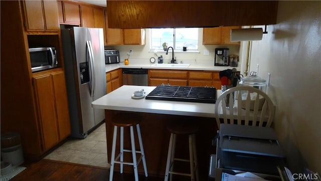 6301 Park Ave, Lake Isabella, CA 93240 - kitchen with light countertops, a sink, a breakfast bar, appliances with stainless steel finishes, and brown cabinetry