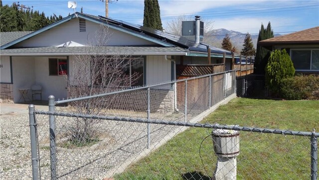 6301 Park Ave, Lake Isabella, CA 93240 - view of property exterior featuring fence, a lawn, roof with shingles, roof mounted solar panels, and a chimney