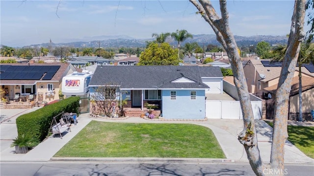 ranch-style house with a front yard, concrete driveway, fence, a residential view, and a mountain view