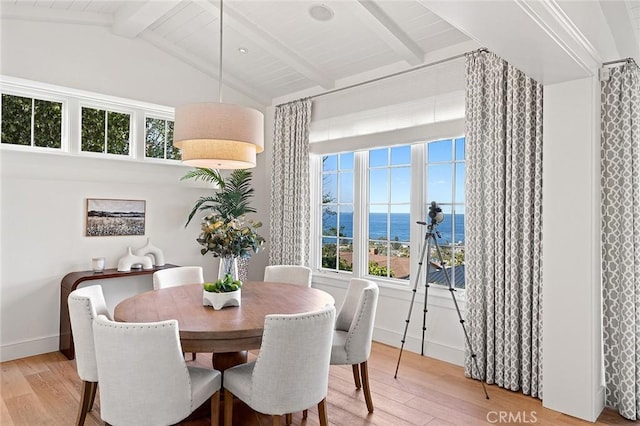 dining room with lofted ceiling with beams, baseboards, and light wood-style floors