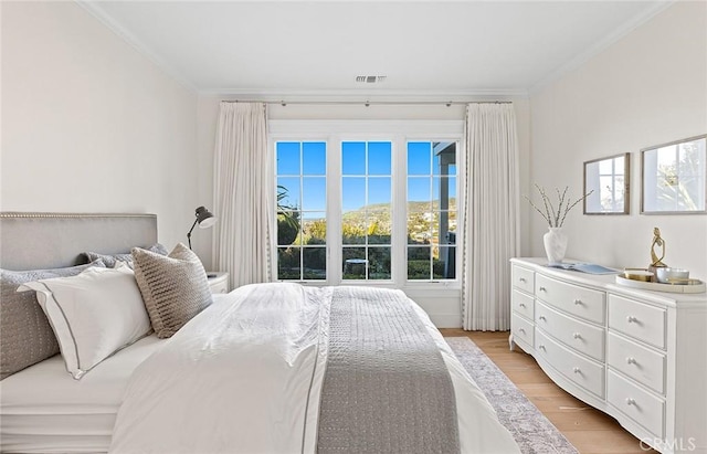 bedroom with crown molding, light wood finished floors, and visible vents