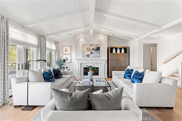 living area featuring a fireplace, vaulted ceiling with beams, wood finished floors, and stairway