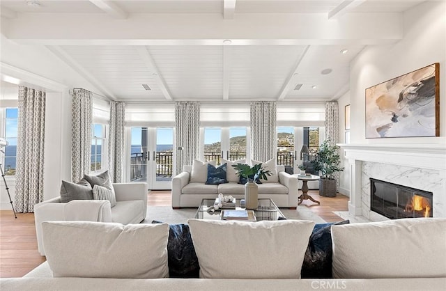 living room featuring vaulted ceiling with beams, a high end fireplace, and light wood-style floors