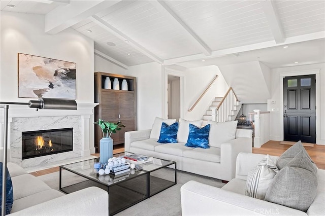 living room with a premium fireplace, wood finished floors, recessed lighting, stairway, and vaulted ceiling with beams