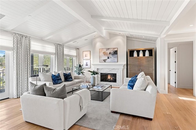 living area featuring light wood-style flooring, lofted ceiling with beams, a fireplace, and visible vents