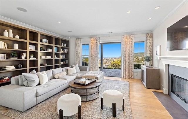 living area with a fireplace with flush hearth, wood finished floors, recessed lighting, and crown molding