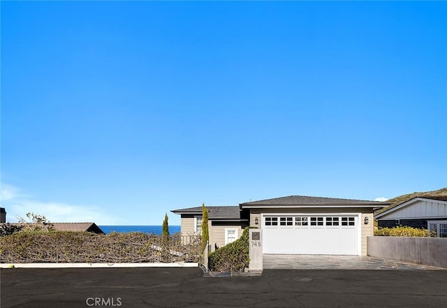 view of front of house with driveway, a water view, and a garage