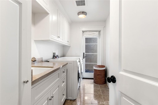 washroom featuring a sink, cabinet space, separate washer and dryer, and visible vents