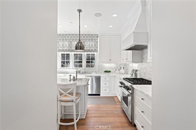 kitchen featuring decorative backsplash, white cabinets, premium range hood, appliances with stainless steel finishes, and light wood-style floors