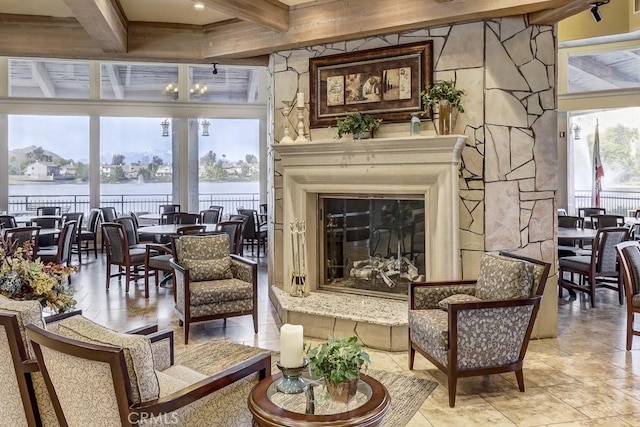 living area featuring a water view, a glass covered fireplace, and beam ceiling