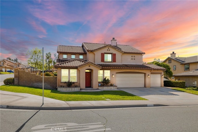 mediterranean / spanish-style home with concrete driveway, a chimney, stucco siding, a tiled roof, and a lawn
