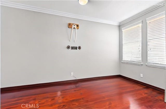 unfurnished room with ornamental molding, baseboards, and wood finished floors