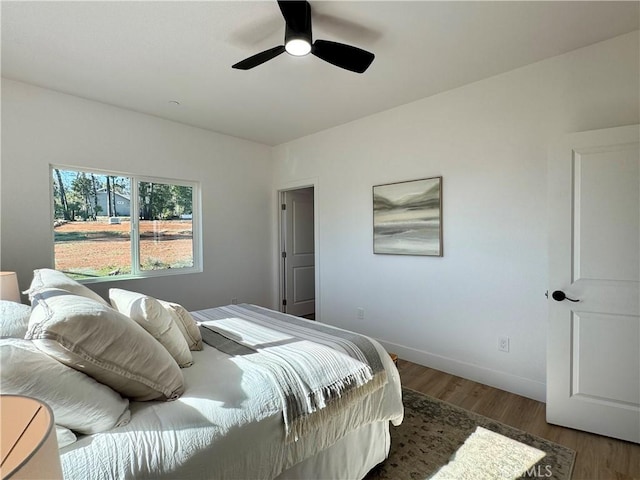 bedroom featuring baseboards, ceiling fan, wood finished floors, and vaulted ceiling