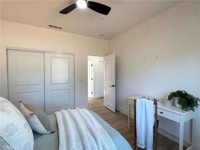 bedroom featuring ceiling fan, visible vents, light wood-type flooring, baseboards, and a closet